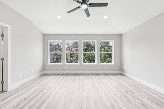 Spare room featuring plenty of natural light, light wood finished floors, a ceiling fan, baseboards, and lofted ceiling | Image 21