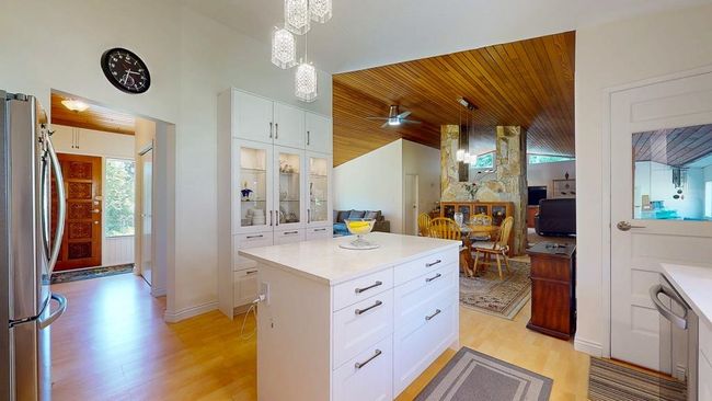 Kitchen with light wood-style floors, wood ceiling, light countertops, and white cabinets | Image 7