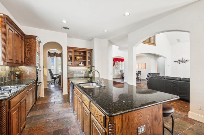 Kitchen featuring kitchen island with sink looking into the living area | Image 9