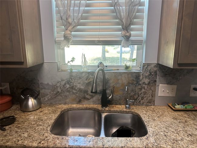 Kitchen with a sink, backsplash, and light stone countertops | Image 32