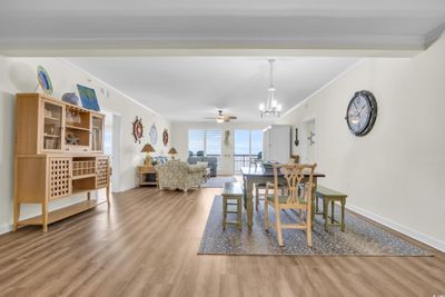 Dining space with crown molding, light hardwood / wood-style flooring, and ceiling fan with notable chandelier | Image 2