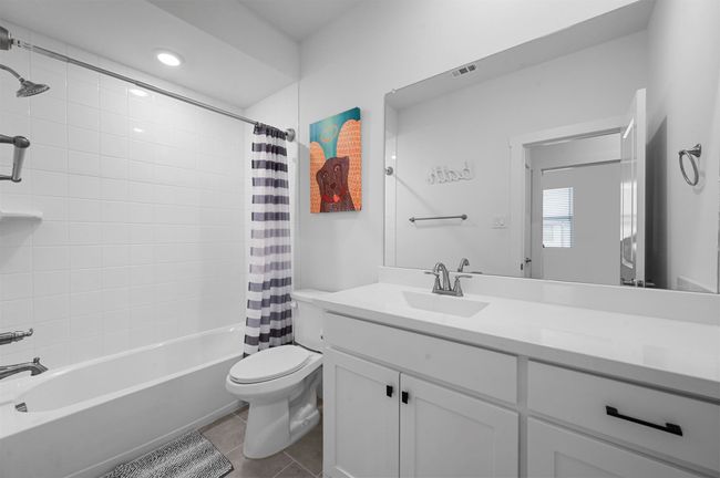 Full bathroom featuring vanity, shower / tub combo with curtain, tile patterned floors, and toilet | Image 13