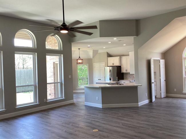 Kitchen with freestanding refrigerator, white cabinetry, light countertops, dark wood-style floors, and pendant lighting | Image 6