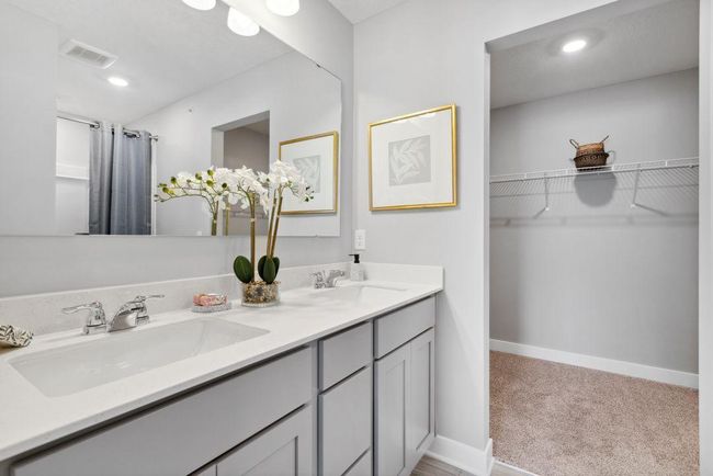 A peak inside the bathroom off the Primary Suite. Notice the extra high cabinets and double-bowl Quartz covered vanity with loads of storage! Photo is of model home. Colors and options may vary. Ask Sales Agent for details. | Image 26