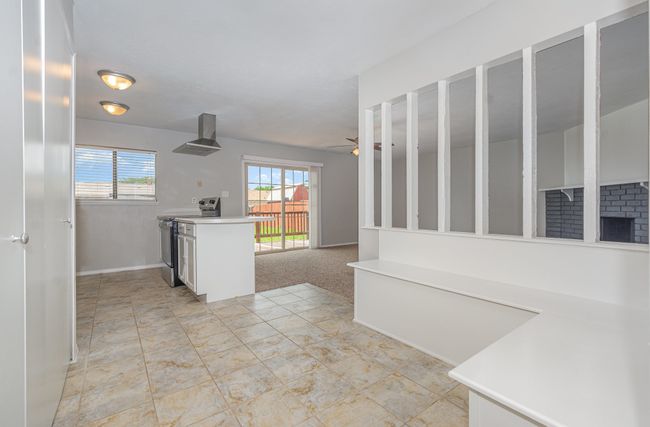 Kitchen with electric stove, wall chimney exhaust hood, plenty of natural light, and light countertops | Image 10