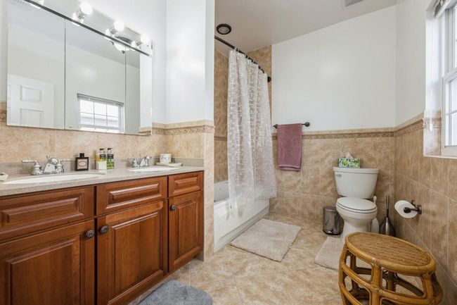 Full bathroom with tile walls, a wealth of natural light, toilet, and a sink | Image 12