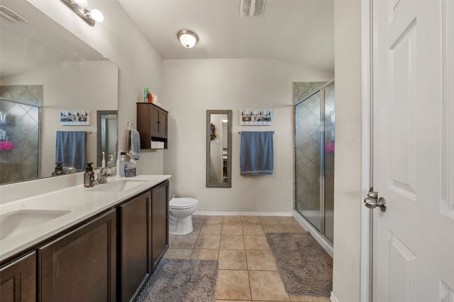 Full bathroom with double vanity, a stall shower, tile patterned flooring, and vaulted ceiling | Image 12