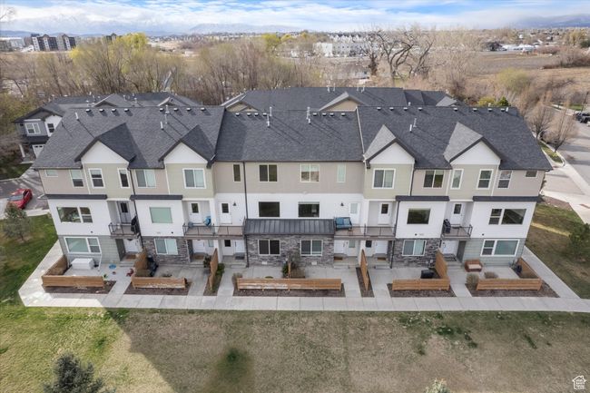 Rear view of property with stone siding, a patio area, a shingled roof, and a residential view | Image 24