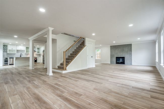 Unfurnished living room featuring crown molding, stairs, a premium fireplace, beverage cooler, and recessed lighting | Image 11