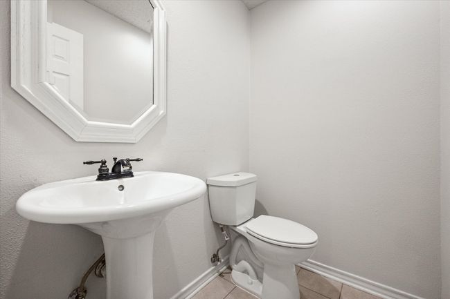 The powder bath is perfect for guests. It features recent paint, ceramic tile floor, an updated toilet and pedestal sink. | Image 27