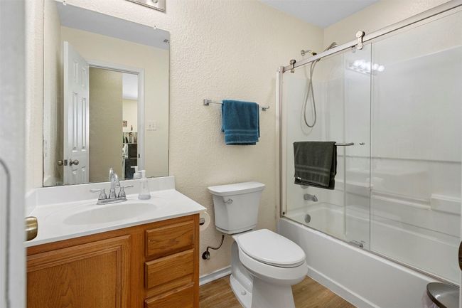 Bathroom with toilet, wood finished floors, vanity, enclosed tub / shower combo, and a textured wall | Image 19