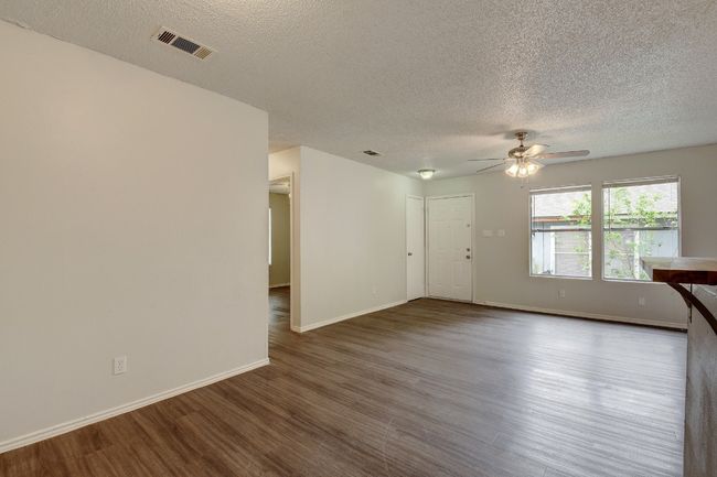 Empty room featuring wood finished floors, a textured ceiling, a ceiling fan, and baseboards | Image 11