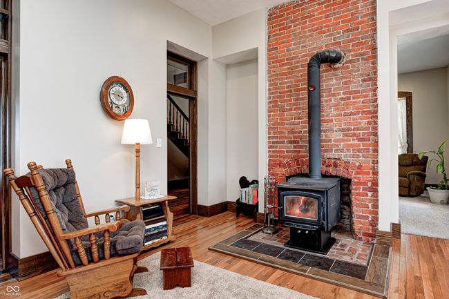 living room with a wood stove, hardwood / wood-style flooring, baseboards, and stairs | Image 16