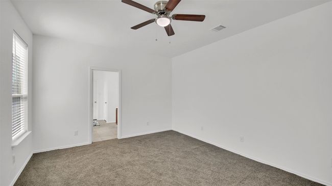 Carpeted empty room featuring ceiling fan, visible vents, and baseboards | Image 21
