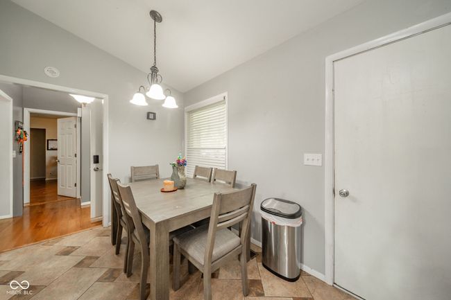 dining space with vaulted ceiling, light stone finish flooring, and a chandelier | Image 16