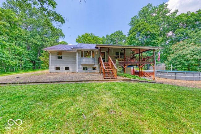 rear view of house featuring stairs, a ceiling fan, a lawn, and a metal roof | Image 56