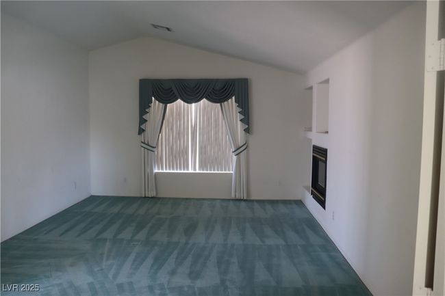 Unfurnished living room with carpet floors, a glass covered fireplace, and lofted ceiling | Image 43