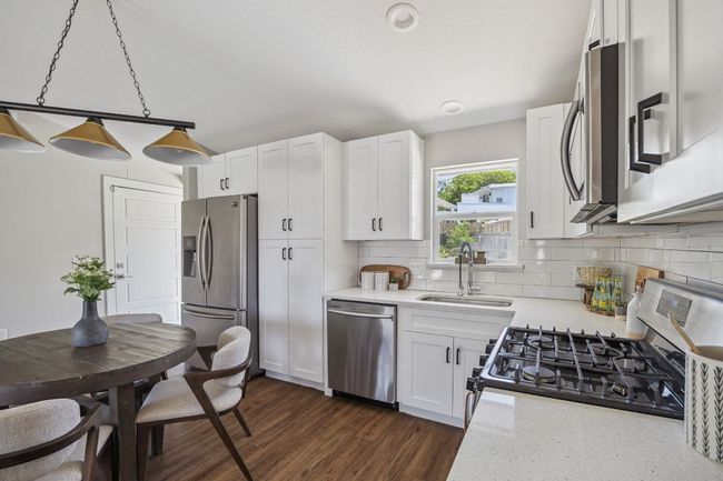 Kitchen featuring stainless steel appliances, tasteful backsplash, and white cabinets | Image 13