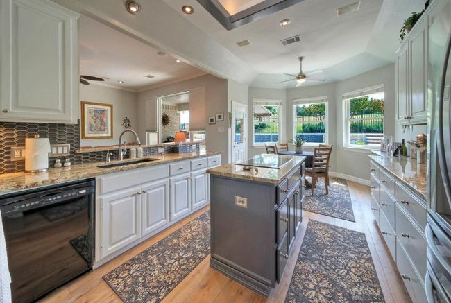 Kitchen with black appliances, a sink, ceiling fan, and visible vents | Image 8