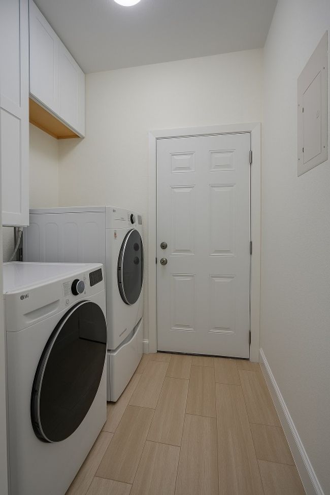 Laundry room featuring washer and dryer, cabinet space, light wood finished floors, and electric panel | Image 20