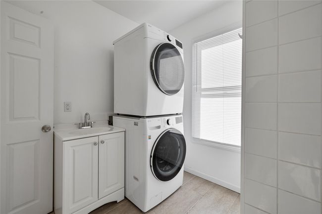 Clothes washing area featuring sink, cabinets, stacked washer and clothes dryer, and light tile patterned floors | Image 18