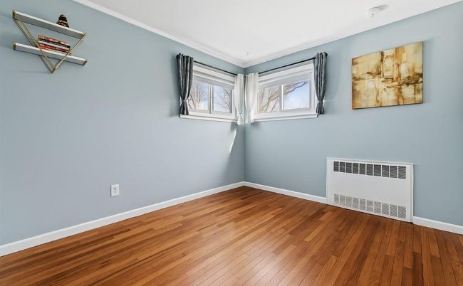 Spare room with radiator, baseboards, ornamental molding, and wood-type flooring | Image 10
