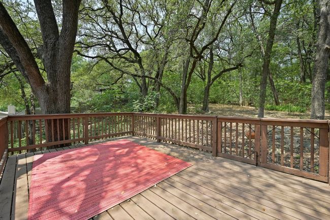 Stairs lead up to a raised deck tucked among mature trees, giving it a secluded, treehouse-like feel. | Image 20