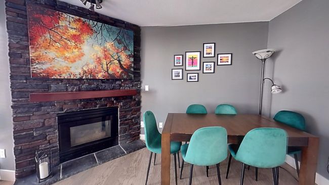 Dining space with baseboards, wood finished floors, and a stone fireplace | Image 4