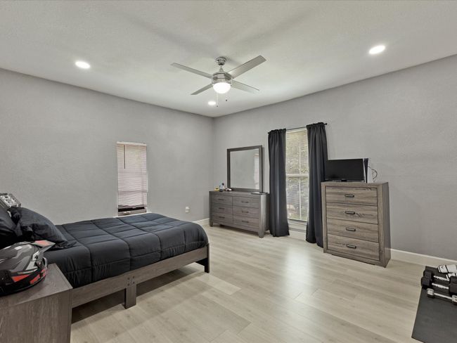 Bedroom featuring light wood finished floors, ceiling fan, recessed lighting, and baseboards | Image 22