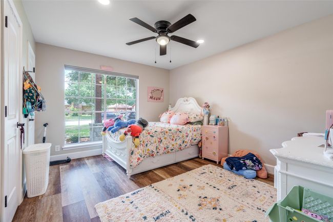 The bright and inviting bedroom features a large window for natural light, stylish vinyl plank flooring, and sleek recessed lighting. | Image 15