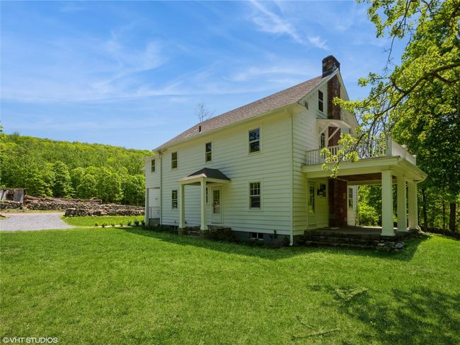 Back of house with a balcony, a chimney, a lawn, and a shingled roof | Image 14