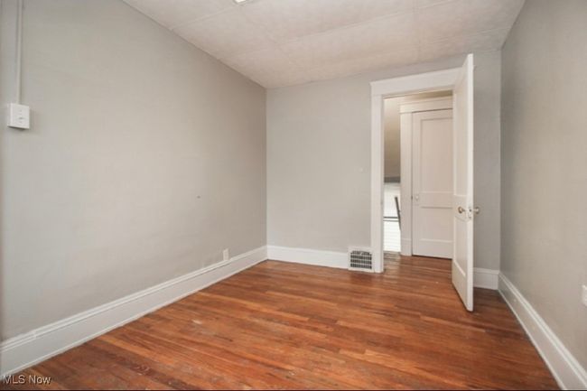 Empty room with wood finished floors and a paneled ceiling | Image 4