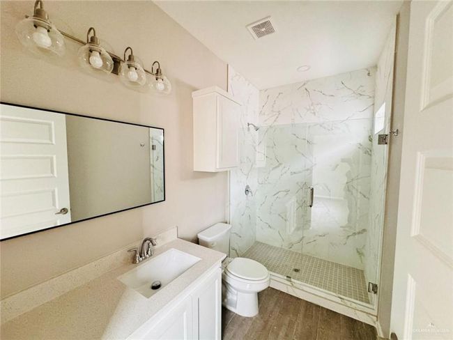 Full bathroom with a marble finish shower, vanity, and wood finished floors | Image 22