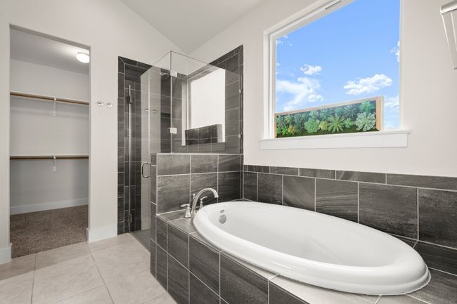 Bathroom featuring a garden tub, a shower stall, a spacious closet, lofted ceiling, and tile patterned flooring | Image 13