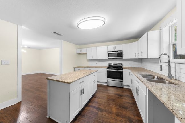 Kitchen with stainless steel appliances, a sink, decorative backsplash, and light stone countertops | Image 11