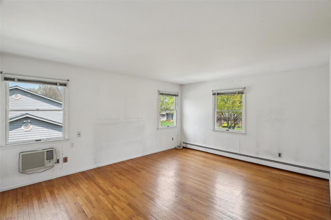 Spare room featuring baseboard heating, baseboards, hardwood / wood-style flooring, and a wall unit AC | Image 23