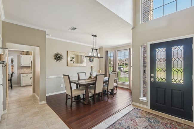 Entrance foyer with crown molding, light tile patterned flooring, and a chandelier. | Image 5