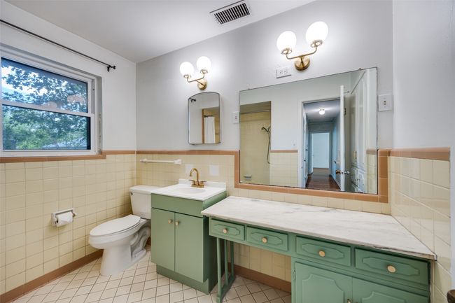 Bathroom featuring tile walls, vanity, a wainscoted wall, and a shower | Image 11