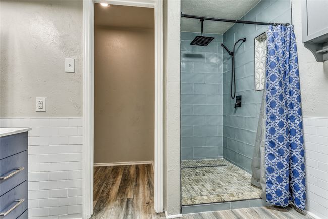 Bathroom with wood finished floors, a stall shower, wainscoting, and a textured wall | Image 21