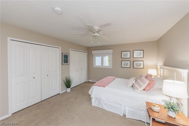 Bedroom featuring light carpet, two closets, and ceiling fan | Image 31