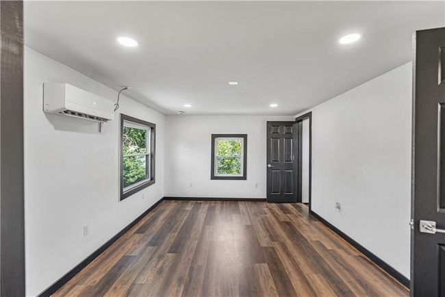 Upstairs bedroom with a wall mounted air conditioner, recessed lighting, dark wood-style floors, and baseboards | Image 39