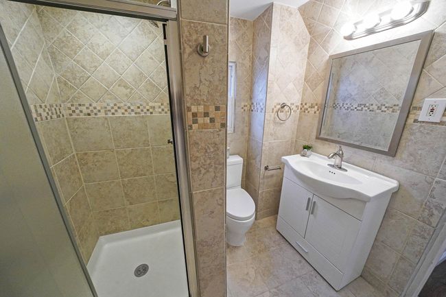 Lower Level Full Bathroom with an Enclosed Shower, Vanity, Toilet, and Tile Walls | Image 27
