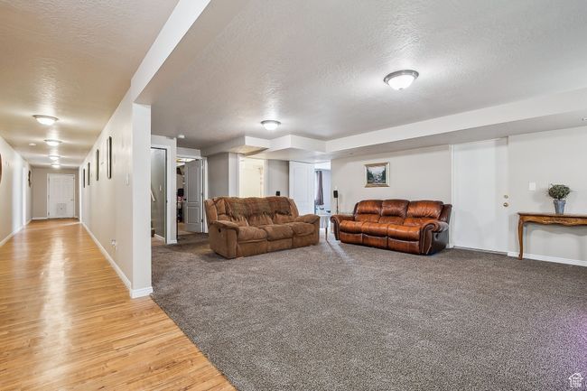 Living room featuring light wood-style flooring, a textured ceiling, and baseboards | Image 39