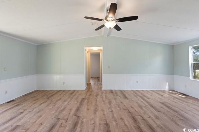 Living room wood finished floors, ceiling fan, a wainscoted wall, and ornamental molding | Image 12