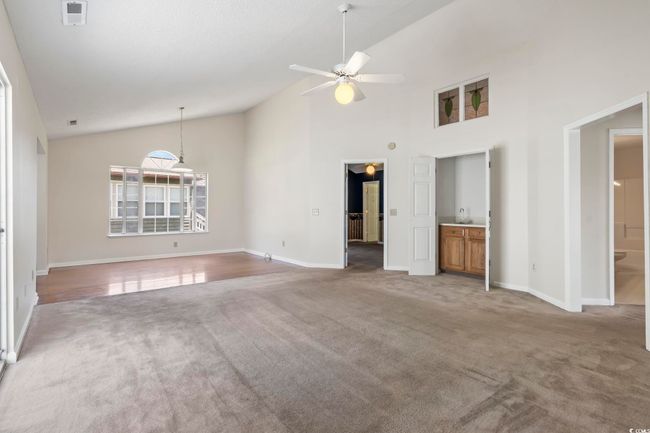 Unfurnished living room featuring a ceiling fan, carpet floors, baseboards, and high vaulted ceiling | Image 11