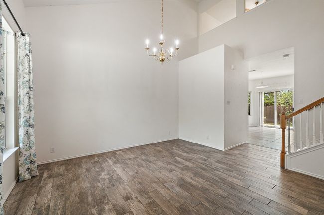 Spare room featuring baseboards, wood finished floors, a chandelier, and stairway | Image 7