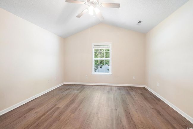 Empty room with wood finished floors, a ceiling fan, and lofted ceiling | Image 25