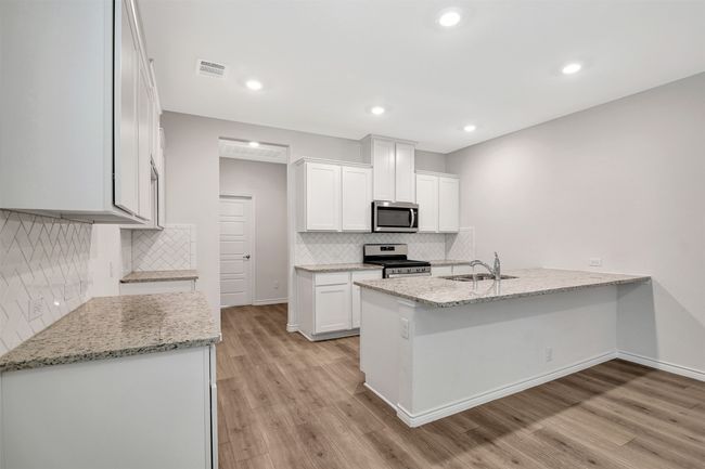 Kitchen with stainless steel appliances, a peninsula, light wood-style flooring, tasteful backsplash, and recessed lighting | Image 4