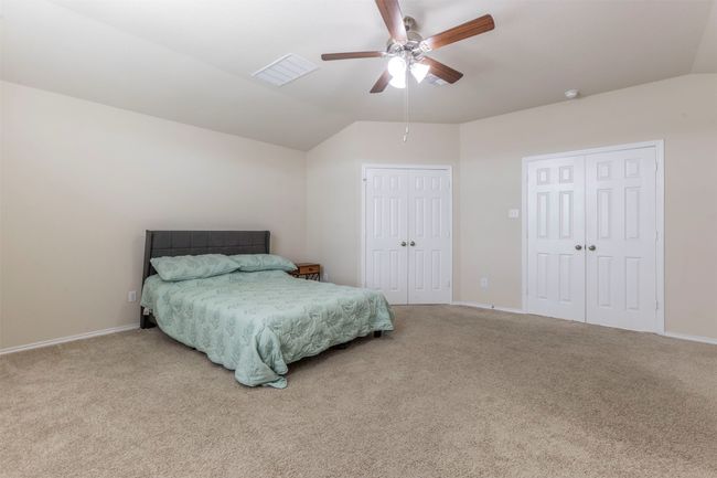 Carpeted bedroom featuring ceiling fan, visible vents, multiple closets, baseboards, and vaulted ceiling | Image 14