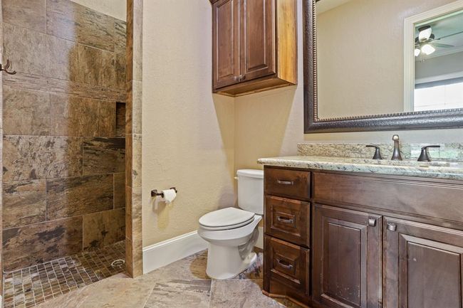 The prior Secondary Bedroom has direct access to this ensuite Bathroom. Equipped with an undermount sink, granite countertop, above and below storage, and walk-in, frameless shower, this space is sure to suit your family’s needs. | Image 36
